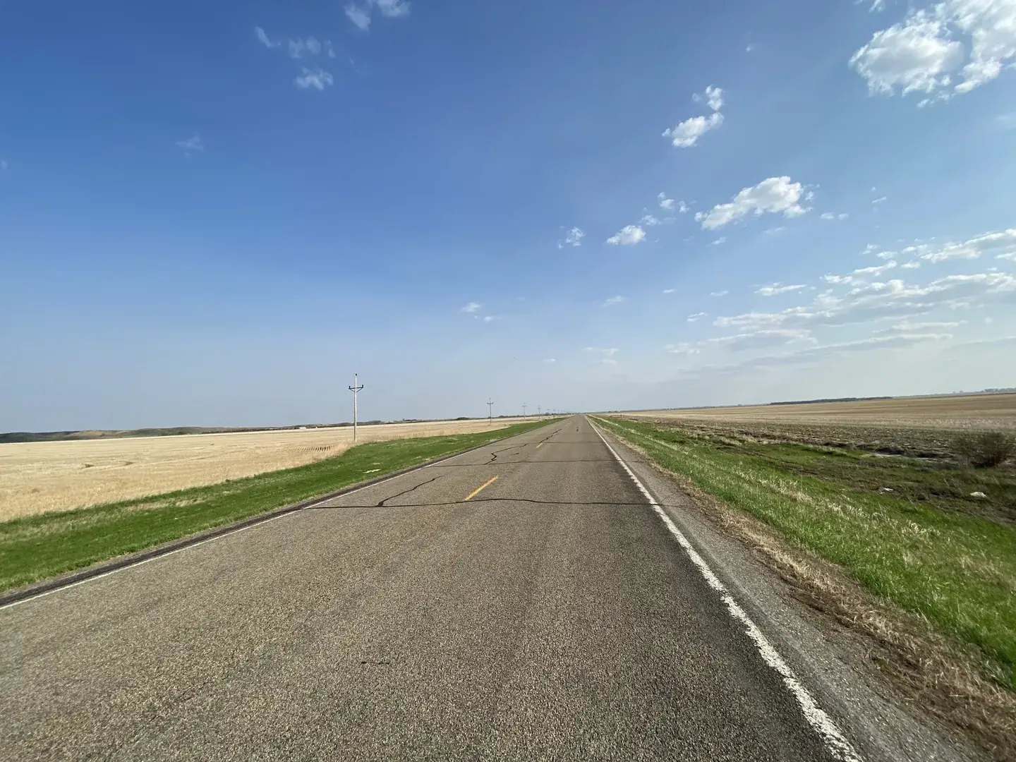 An open road stretching to the horizon under a wide blue sky